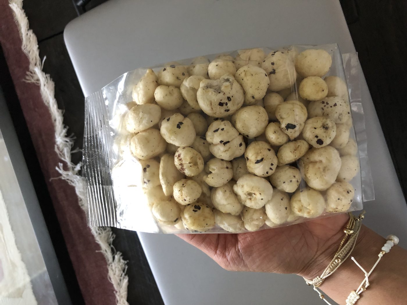 Hand holding a clear bag of FOXPOPS fox nuts